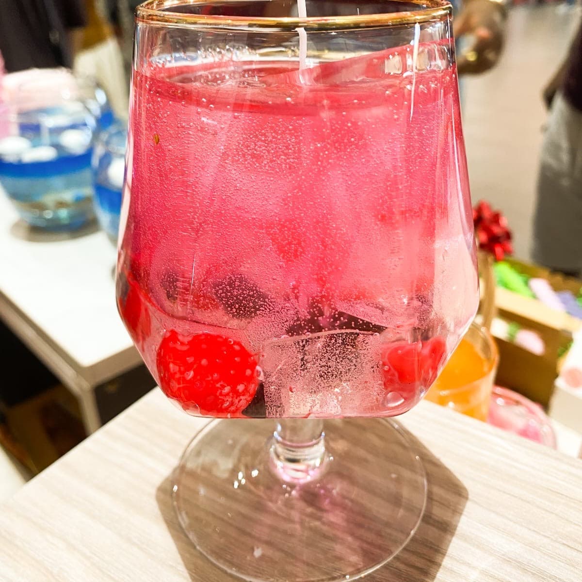 Berry spritz candle — pink gel wax with wax berries in a gold-rimmed glass