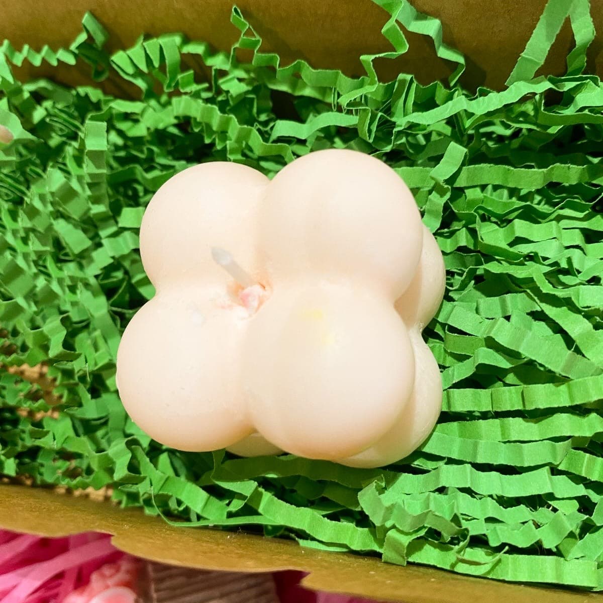Cream bubble cube candle in a kraft gift box on green paper